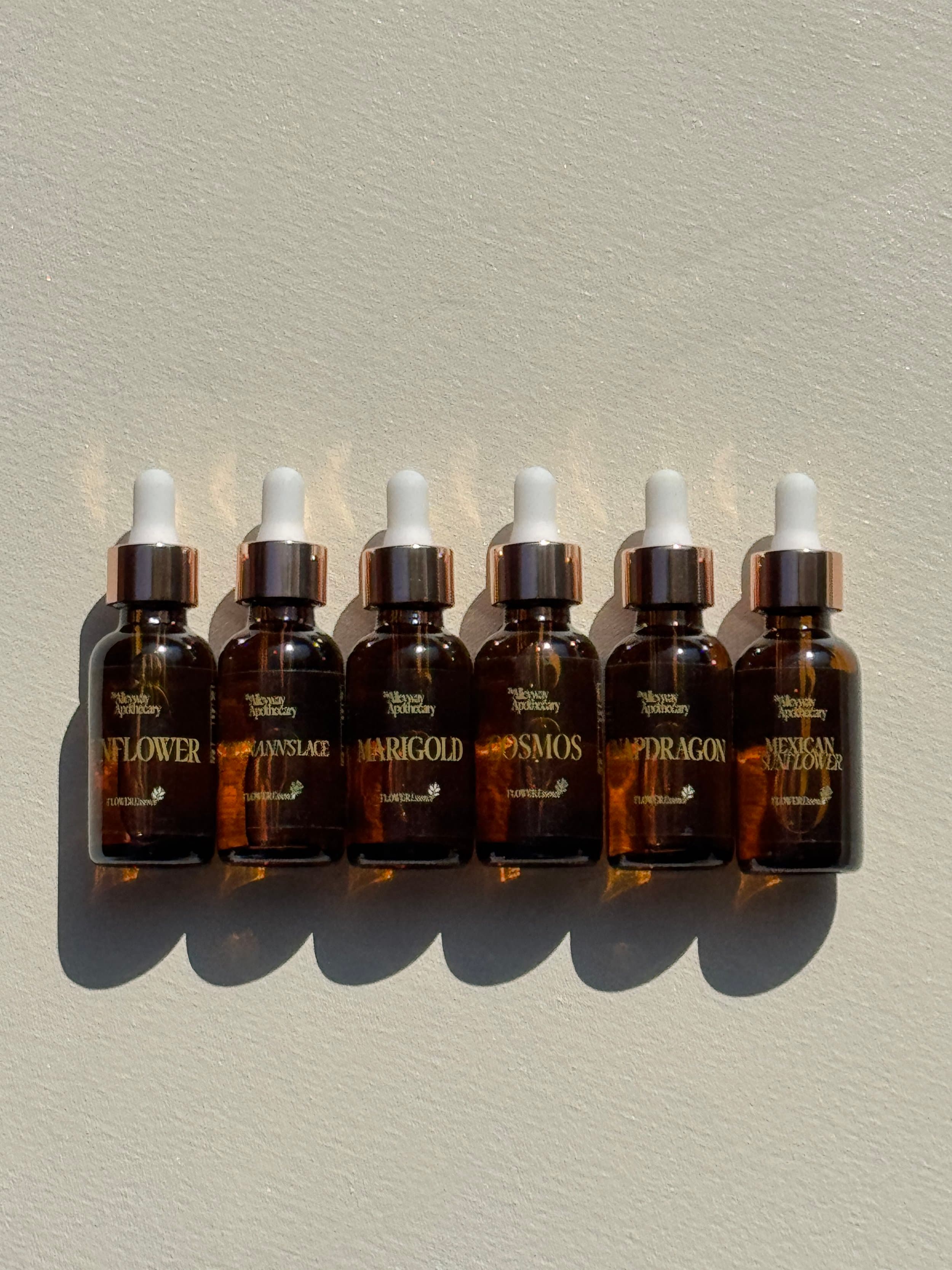 The Alleyway Apothecary flower essence collection bottles on a wooden surface